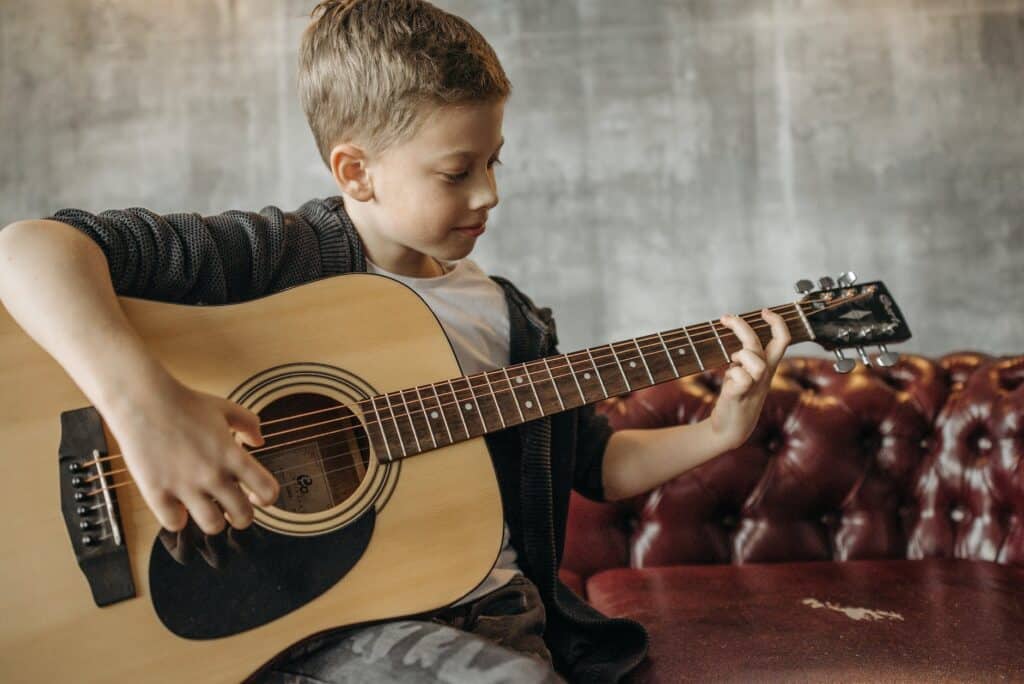 boy wearing a jacket playing a guitar