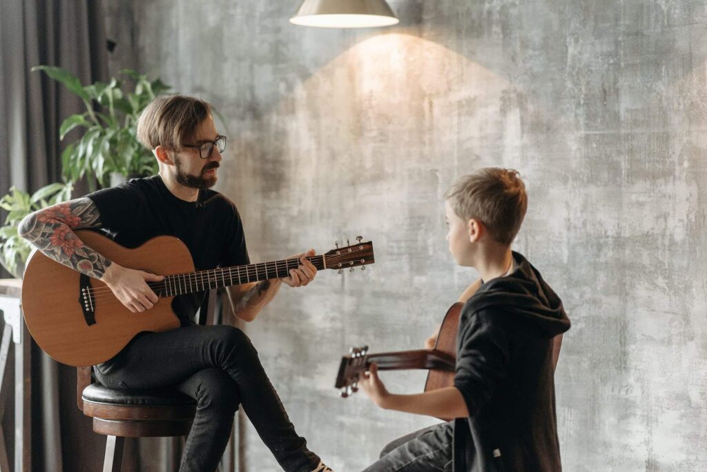 teacher and his student playing acoustic guitar