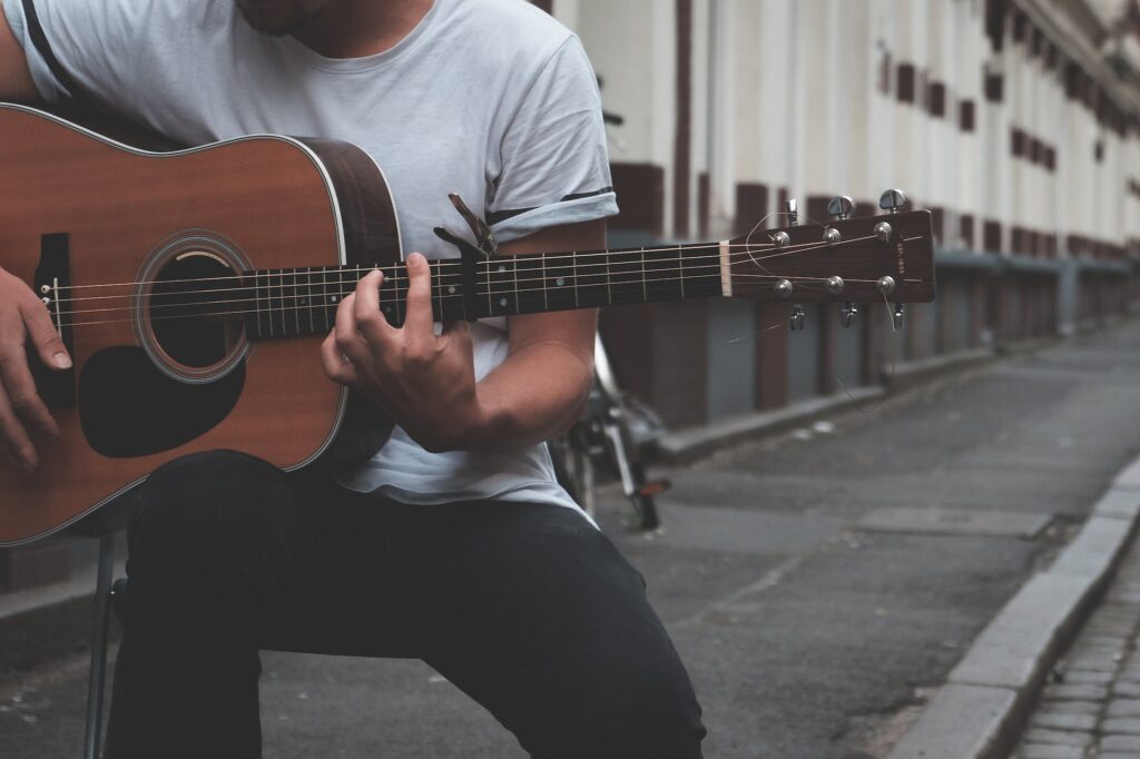 crop guitarist playing on street